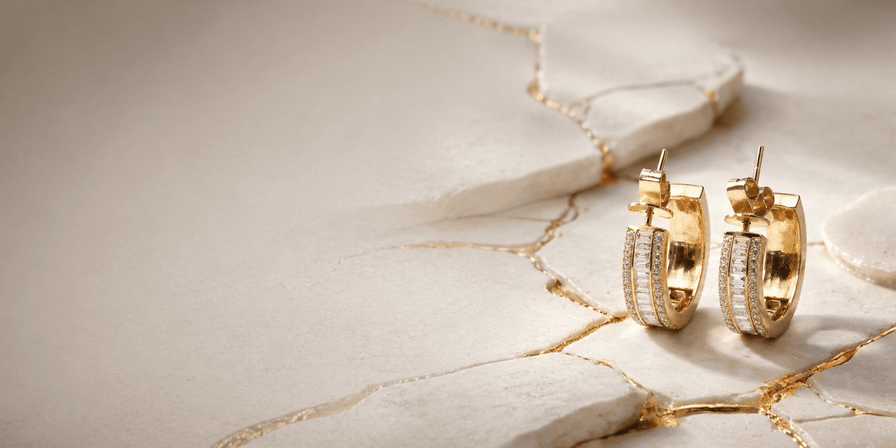 Gold and diamond hoop earrings on marble